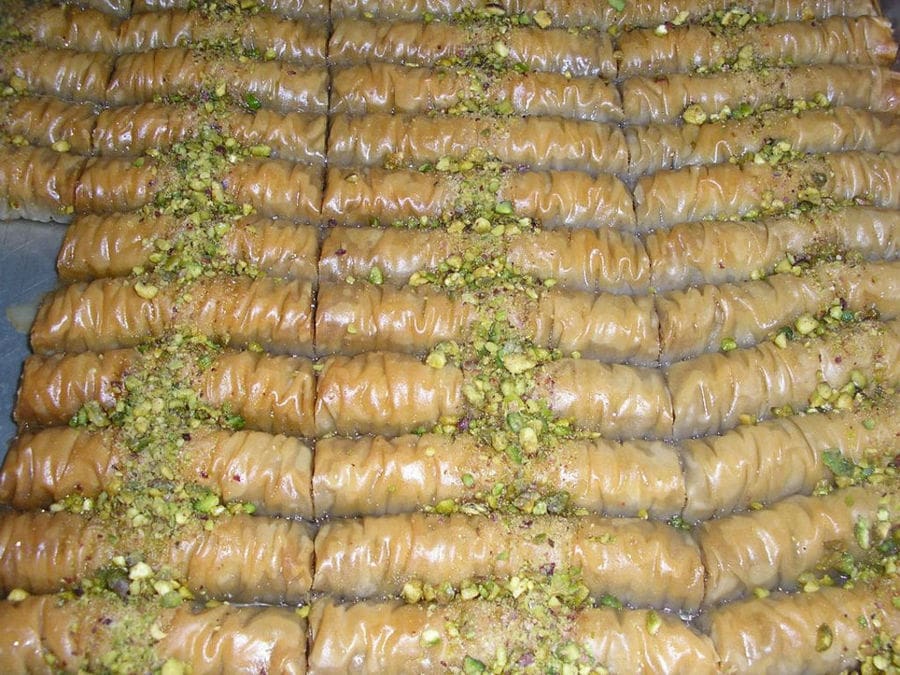 close-up of baking pan with sweet rolls in syrup with ground almonds